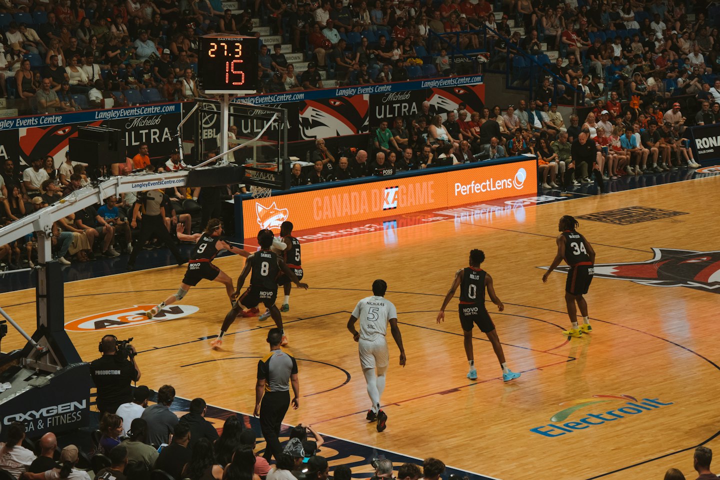 Basketball players compete on a court inside a crowded arena.