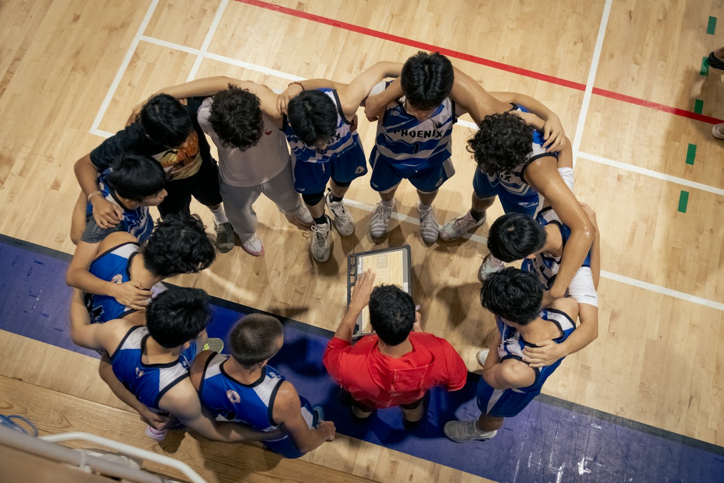Basketball coach explaining strategy to his team on the court.